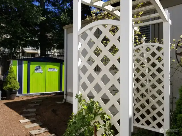 Arbor into backyard with shed.