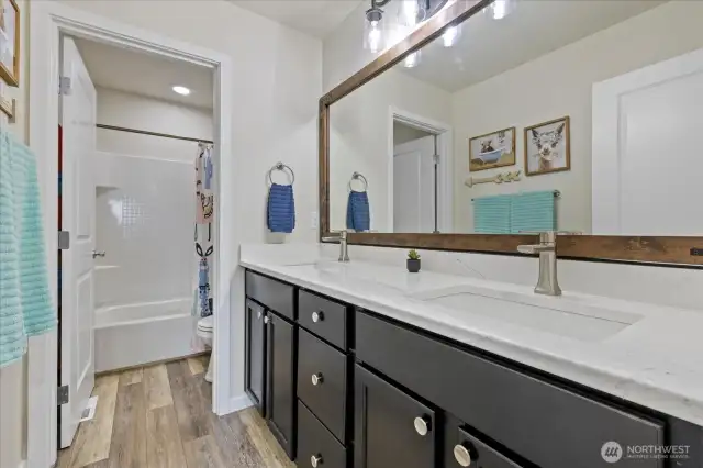 Upstairs Full bath is centrally located adjacent to the rec room and has been updated in 2022 with new LVP flooring, Quartz Countertop, undermount sink and faucet, vanity hardware, new lighting and mirror.