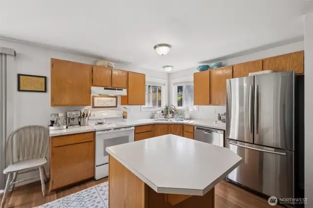 Bright corner kitchen with a center island and new LVP flooring that adds a fresh, modern touch.