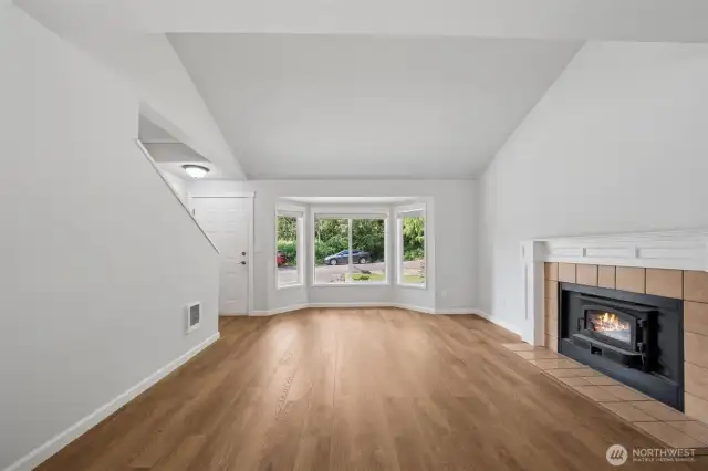 NEW LVP flooring, NEW paint, wood fireplace insert, front facing bay window & vaulted ceilings- will you occupy this side or will you rent it?