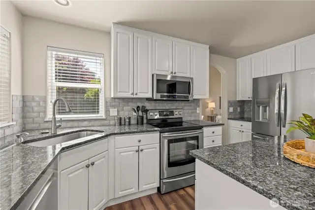 Large open kitchen with updated, stainless appliances, and island flowing to the family room and backyard patio.