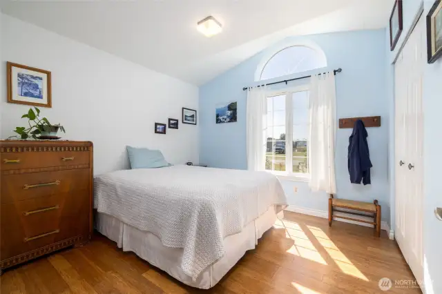 Guest bedroom with lovely half-circle window and vaulted ceiling.  Bamboo flooring.