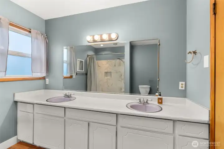 Spacious full bath featuring dual sinks, updated lighting and ample storage, a clean, refreshed design to serve the household with ease.