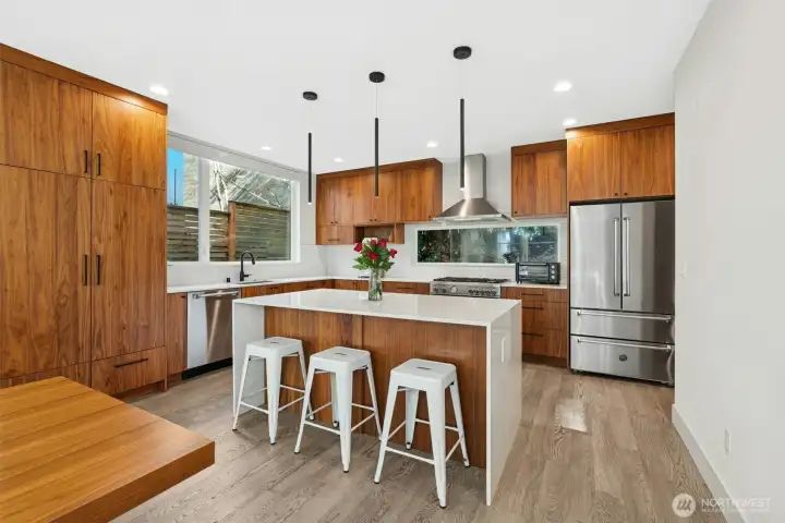 Chef’s island kitchen features rich walnut cabinetry, quartz slab counters, & high-end stainless-steel appliances