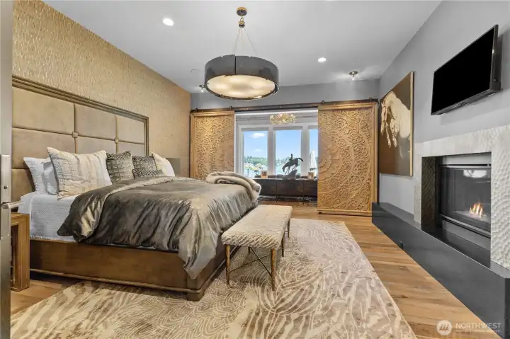 Main level - Large Primary bedroom with sitting area suite –   Premium grade bamboo wall covering  Pecky cypress ceiling in sitting area with antler chandelier  Specialized antique carved doors to close off sitting area  Custom steel mantel – gas fireplace