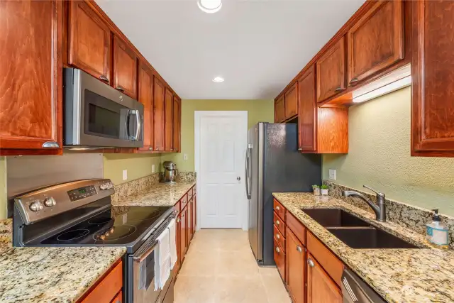 This glorious kitchen enjoys custom cabinetry, granite, new appliances and new tile! The door at the back leads to a separate laundry room (yay!) and a wonderful one-car garage!