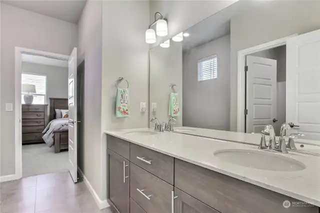 The upstairs guest bathroom offers both style and convenience, featuring double sinks, luxurious quartz countertops, tile flooring, and a tub/shower combo. A well-appointed space designed to accommodate guests or family with ease and sophistication!