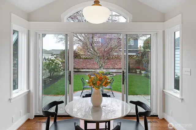 Framed by expansive sliding glass doors and an elegant arched transom, this light-filled dining area offers a stunning view of the meticulously landscaped backyard. Natural light pours in, highlighting the crisp solid wood millwork and warm hardwood floors.
