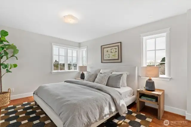 Each of the three upstairs bedrooms features its own private en-suite bath, offering ideal accommodations for guests, family, or flexible living. Designed to comfortably fit king-size beds, each light-filled room is well-proportioned and appointed with hardwood floors, classic trim details, and generous custom closet systems behind paneled doors.