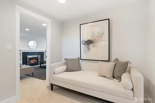 A spacious hallway at the base of the stairs creates a natural transition between living areas, offering a quiet nook for reading or relaxation with a cozy view into the adjacent family room.