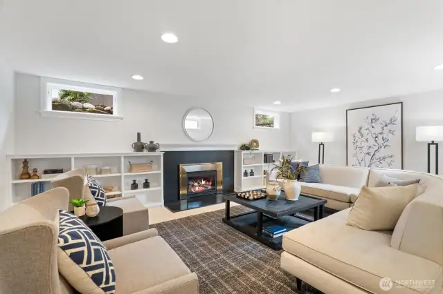 The lower-level family room offers a warm and inviting retreat, centered around a sleek gas fireplace flanked by built-in shelving. With recessed lighting, ample seating, and natural light from above-grade windows, it’s the perfect space for relaxed gatherings or cozy evenings in.