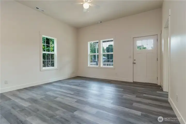Front door into living room with ceiling fan