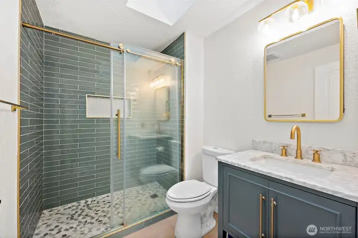 Primary en-suite 3/4 bath fully remodeled with walk-in tiled shower with glass door and gold finishings