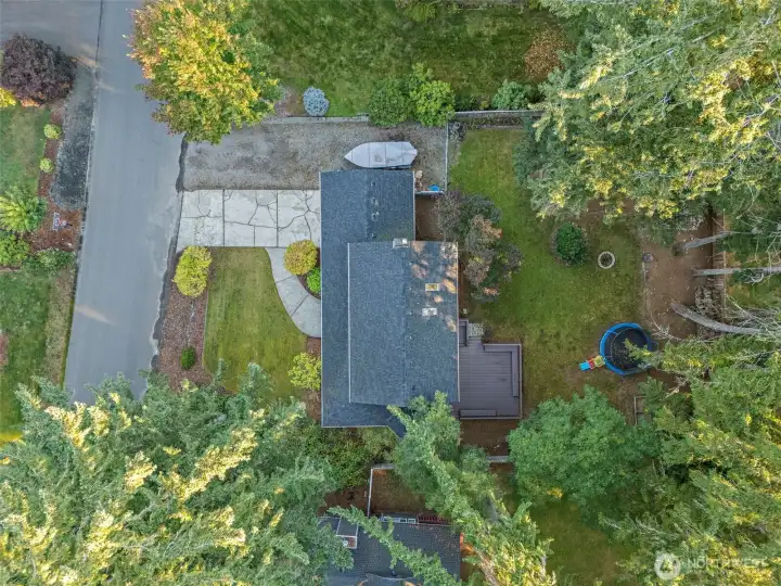 Birds eye view showing the large backyard, side gravel parking area for RV and boat/toy storage alongside the driveway.