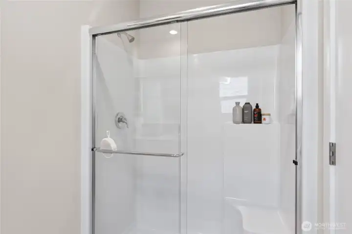 Step-in shower with built in bench in primary bathroom. Actual home is under construction. Colors, materials, and features may vary. See site agent for details.