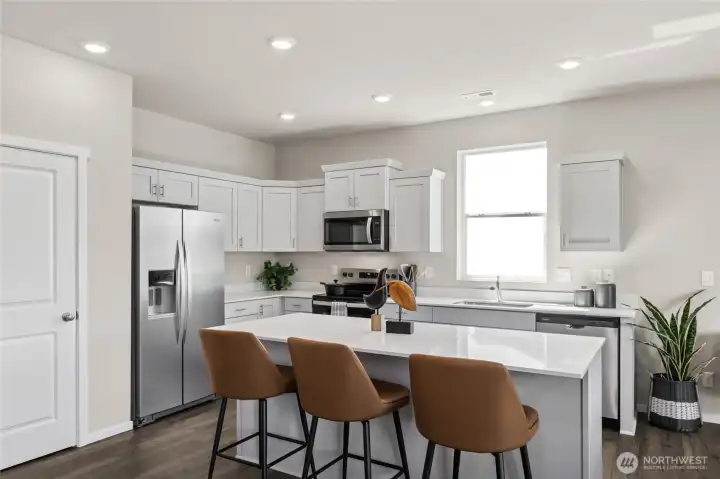 Large kitchen features shaker style cabinets with soft close doors and quartz countertops. Actual home is under construction. Colors, materials, and features may vary. See site agent for details.