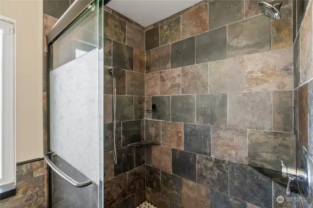 Large primary bath walk-in shower with double shower heads and slate tile.