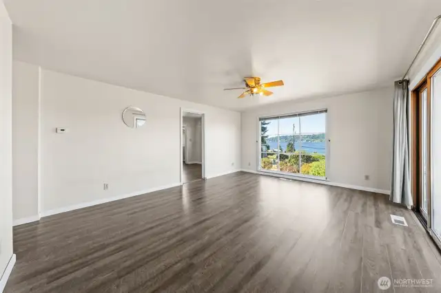 A spacious living room features large picture windows that fill the space with natural light, along with a glass slider offering another easy access point to the yard.
