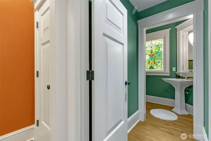 An elegant main floor powder room with a stained-glass window that cleverly disguises a secret window