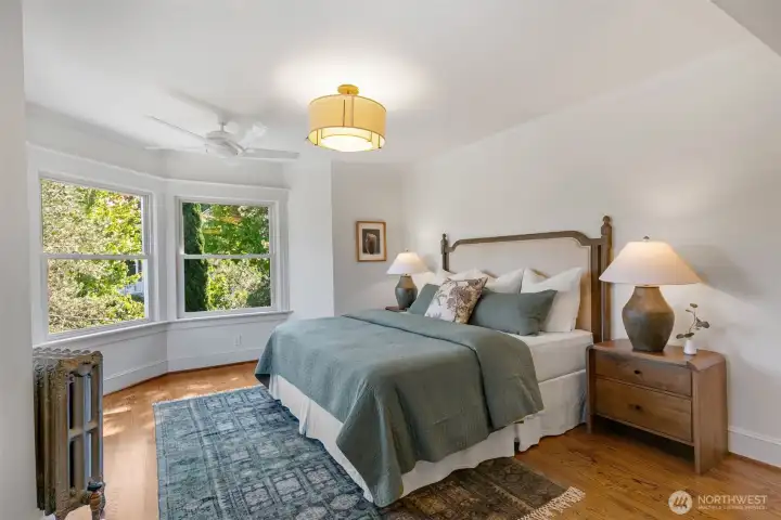 Wake up to sunlight in the grand primary suite, featuring bay windows, a private bath and spacious walk-in closet with custom storage