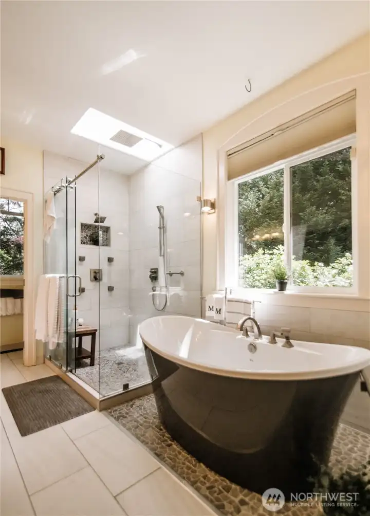 Large soaking tub and a rain shower with a skylight above.