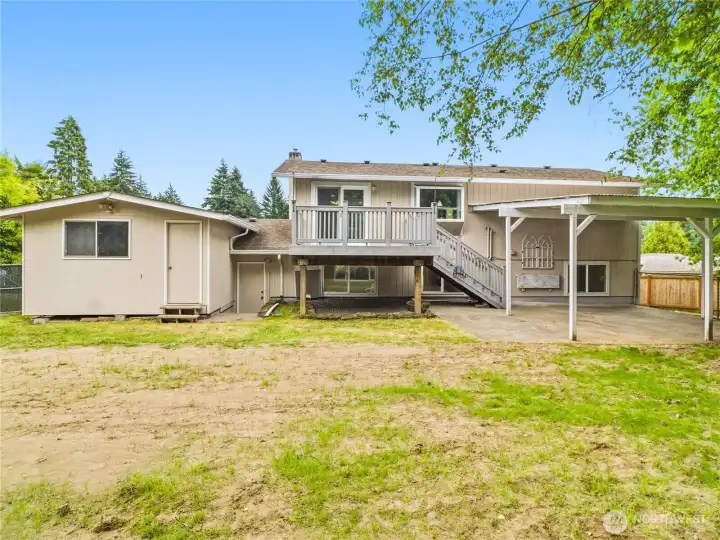 Large attached storage shed behind garage with tons of space + shelving.