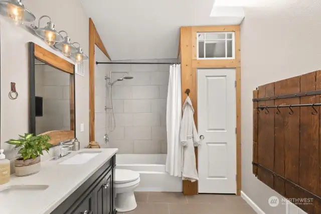 Gorgeous & spacious guest bath with high ceilings, stunning natural light via skylight, linen closet, double vanity, and heated floors!