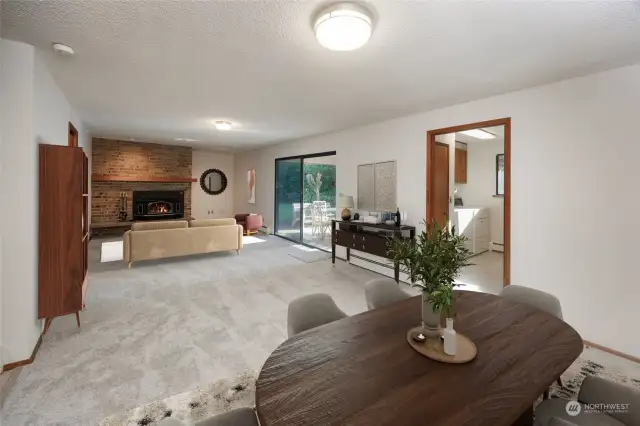 Kitchen dining area towards Family Room with wood burning insert, floor-to-ceiling brick fireplace. Slider doors to back covered patio. Door on right leads to laundry room and 3/4 bath