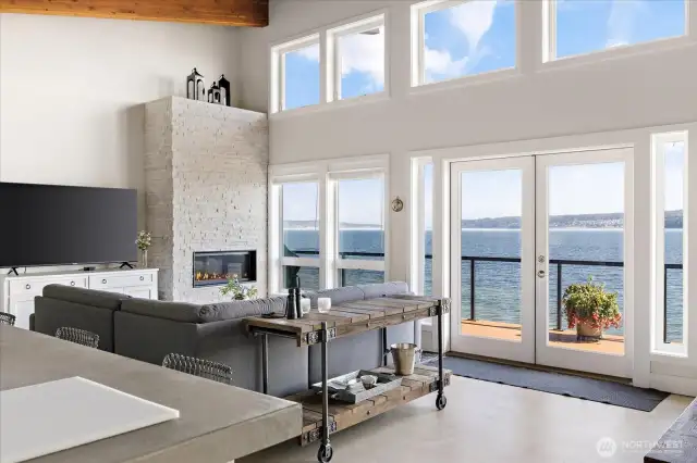 The living room is designed to wow, with a soaring 9–14’ ceiling, and a full wall of windows capturing the shoreline’s beauty.