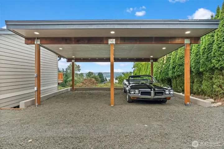 Covered timber-frame carport with recessed lighting and water views through the structure