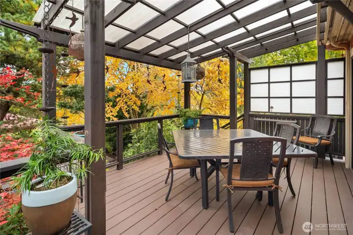 Low-maintenance composite deck with covered arbor, privacy screens, wired temple lanterns, and rain chains.