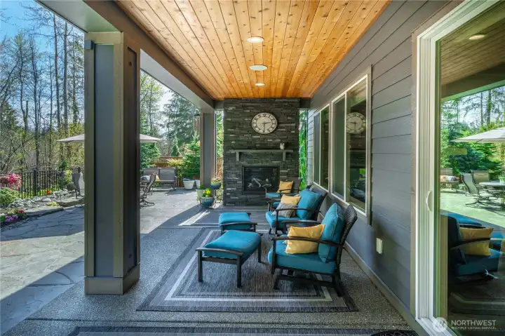 One of two inviting outdoor living spaces. Step out onto the raised patio which enjoys glorious vistas of this stunning outdoor space. The custom stained wood ceiling with surround sound and custom stone fireplace.