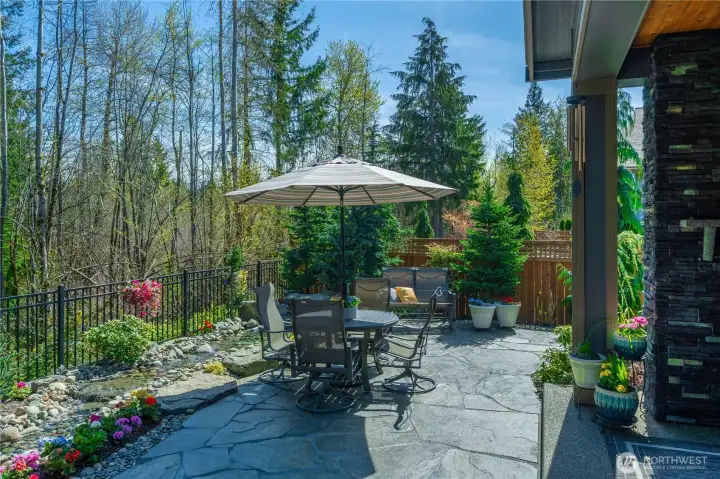 The stunning water feature serves as the backdrop for this amazing yard. Extensive Flagstone (set on a concrete base) and meticulously landscaped, all overlooking the beautiful permanent greenspace.