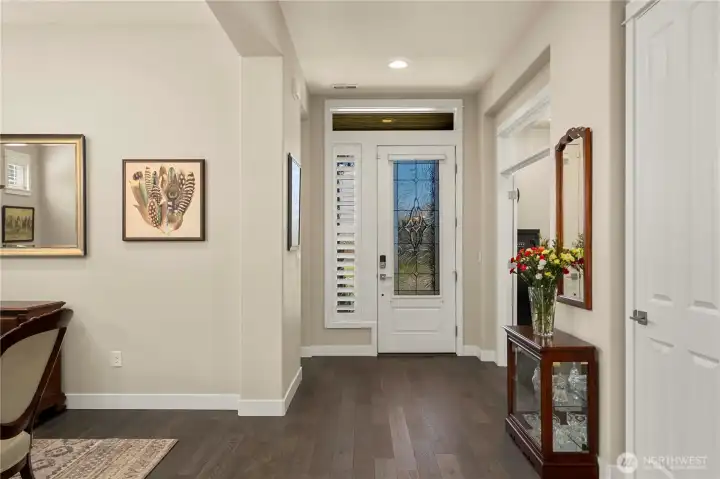 The beautiful entryway with anupgraded front door, Plantation shutters and custom "rain" side window, French doors open to the spacious den.