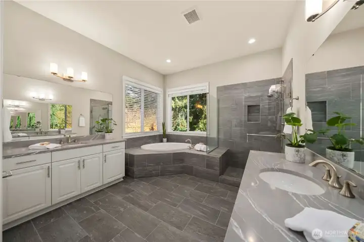 The luxurious primary 5-peice bath with striking Quartz counters, tile floors, tub deck and shower with an upgraded glass enclosure, bench and shower wand. You will feel like you have your own personal spa at home!