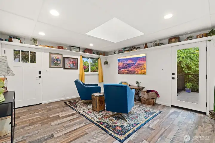 Entrance into the living room has plenty of light with ceiling lights, skylights, windows and glass door out onto private back deck.  Architectural details include a coffered ceiling and a charming perimeter display ledge for books, art, or décor.