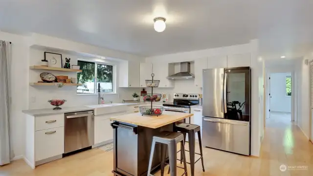 This updated kitchen is a dream featuring white cabinets, large apron sink, high end stainless steel appliances and island with breakfast bar seating.