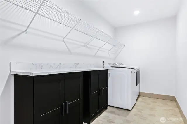 Sprawling laundry room offers great lighting and plenty of storage shelving and matching cabinetry.  Large folding counter makes folding a lot easier and the floors are easy to clean