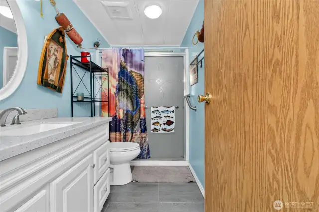 The guest bath has been beautifully updated, featuring a walk-in shower, stylish cabinetry, a modern sink, and warm, inviting lighting.