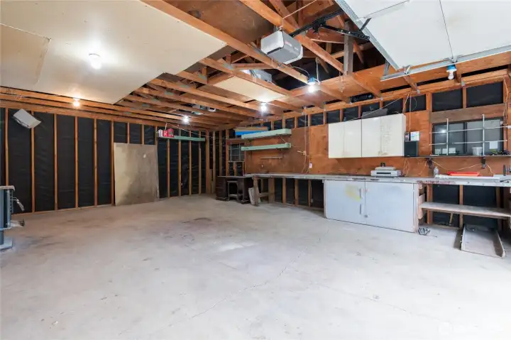 Interior of the large shop.  The shop also has a very tall additional enclosure for RV storage.  There is also drop down access for attic storage.  This is a very deep garage/shop.  There is a large wood stove as well as workbench/storage area.