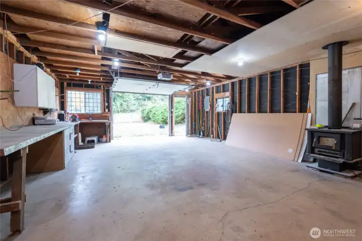 Interior of the large shop with electric garage opener.  The shop also has a very tall additional enclosure for RV storage.  There is also drop down access for attic storage.  This is a very deep shop.