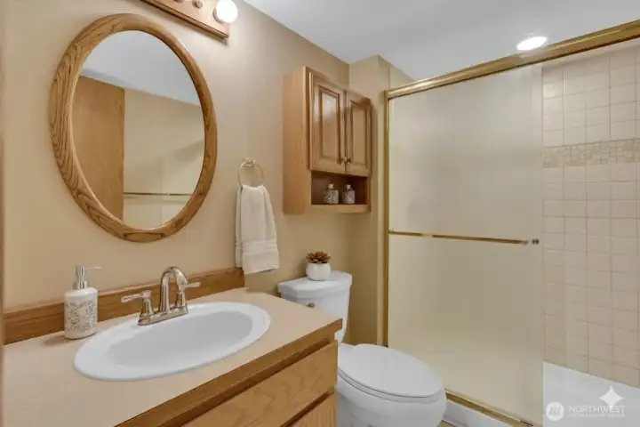 Large three-quarter bath has oak features and a pretty ceramic tiled shower.