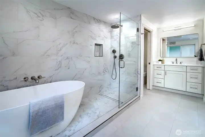 Completely remodeled primary bathroom with beautiful tile work, multiple vanities, soaking tub and shower.