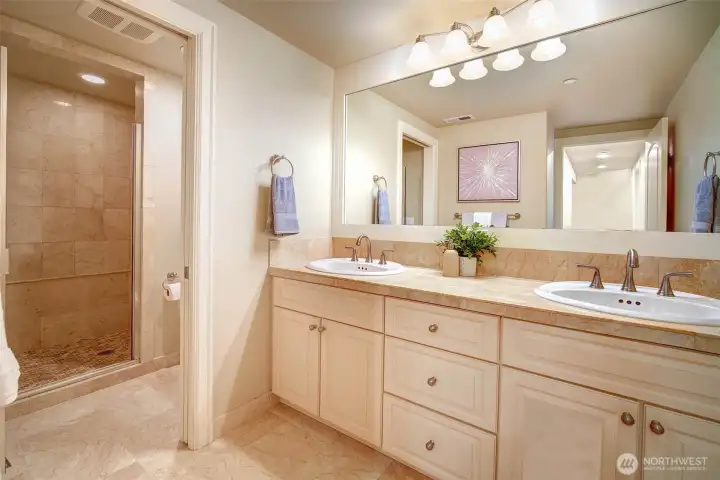 Lower level three-quarter bath with double vanity and elegant tile designs.