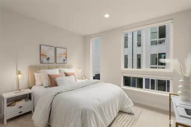 Escape to this inviting bedroom, where large windows draw light and soft neutral tones to create a peaceful retreat.