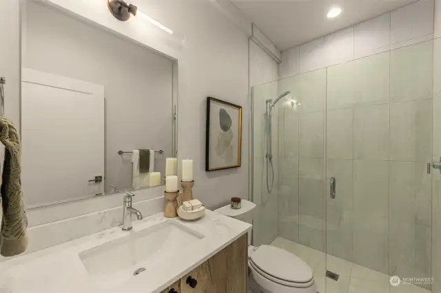 Enjoy a spa-like experience in this chic bathroom, with a spacious glass-enclosed shower and modern fixtures.