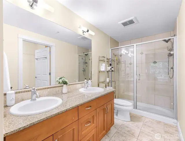 Primary bathroom with dual vanity and large shower, walk in closet adjacent to vanity