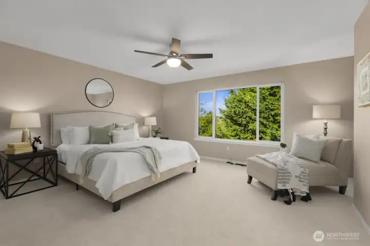 Spacious primary bedroom with large window, seating area, and serene views.