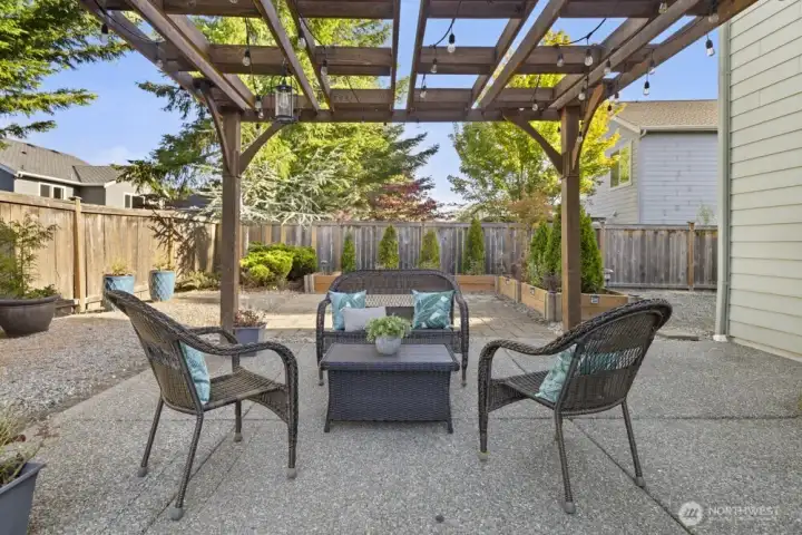Patio with pergola and string lights creates an inviting outdoor living space.