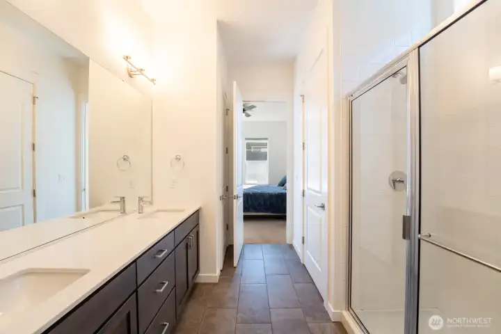 Beautiful tiled primary bath with walk-in shower, double vanity, private toilet, linen closet, and walk-in closet.